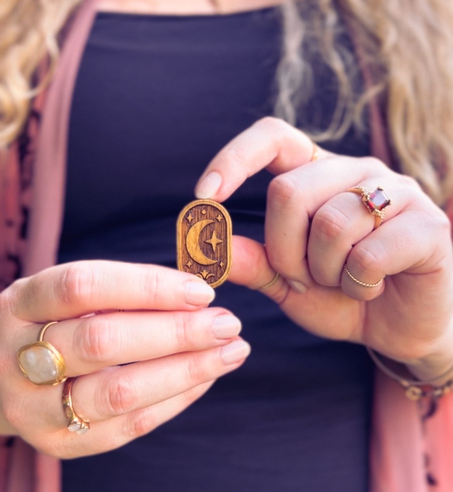 A carved wooden moon and star charm held between two hands