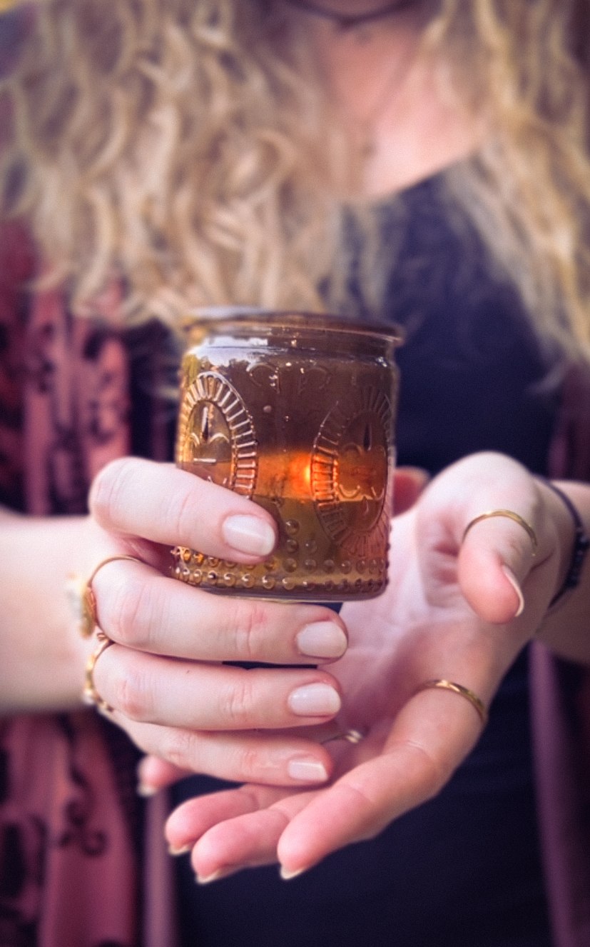 Hands cupping a glowing embossed candle jar